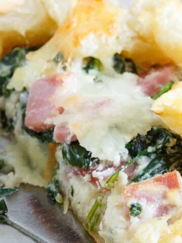 ham, cheese and spinach pie cut in half on a baking sheet