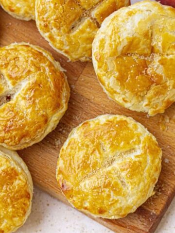 golden round mango pies on a wooden chopping board