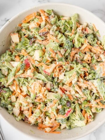 Creamy Broccoli Apple Salad with carrots walnuts and dried cranberries in a bowl ,