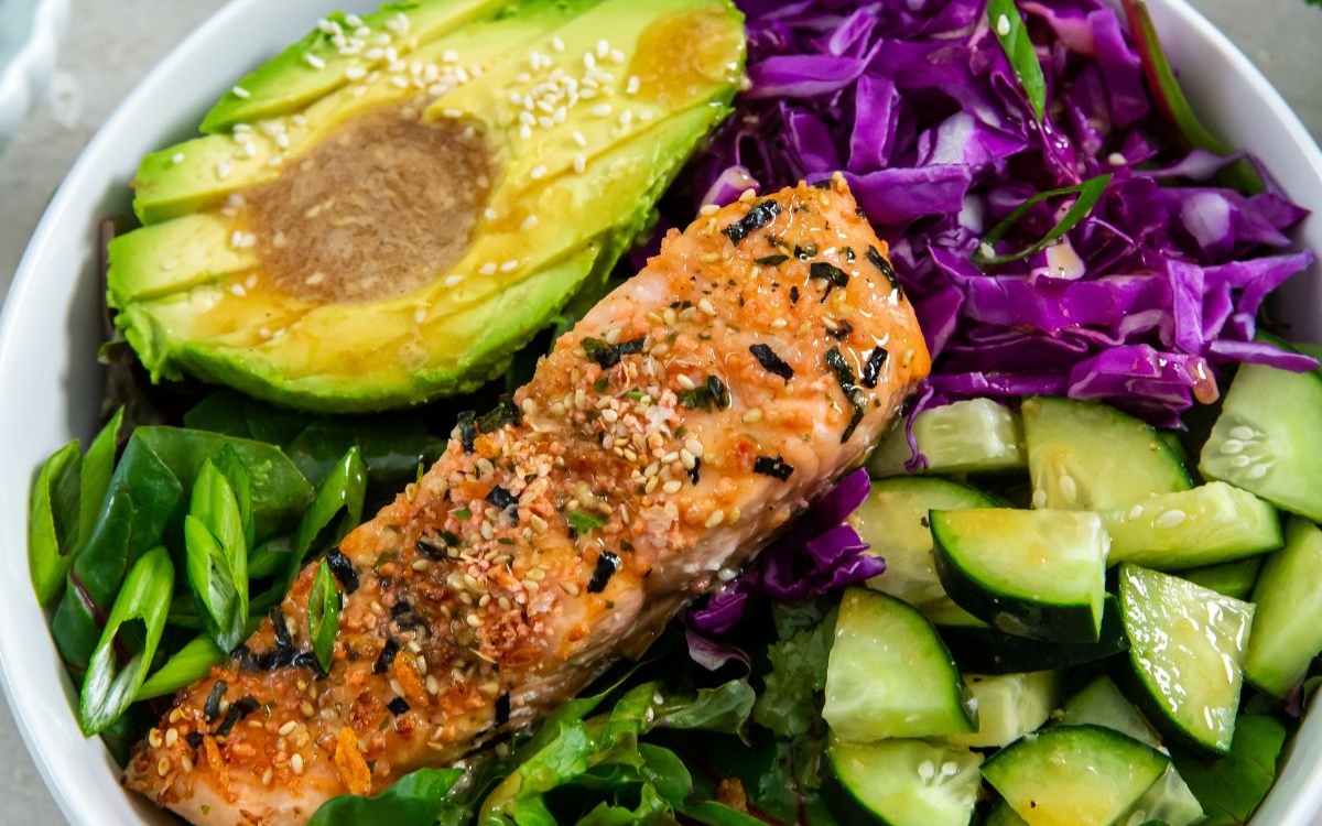avocado, salmon, red cabbage cucumber and scallions on a bowl