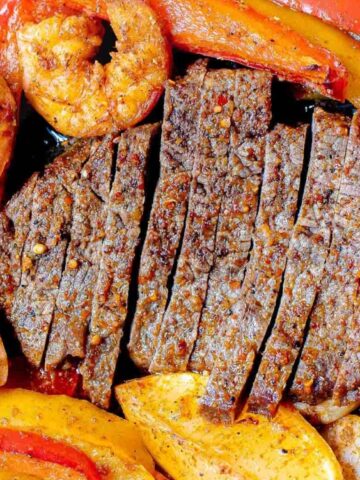 sliced fajita steak with shrimp, peppers and onions