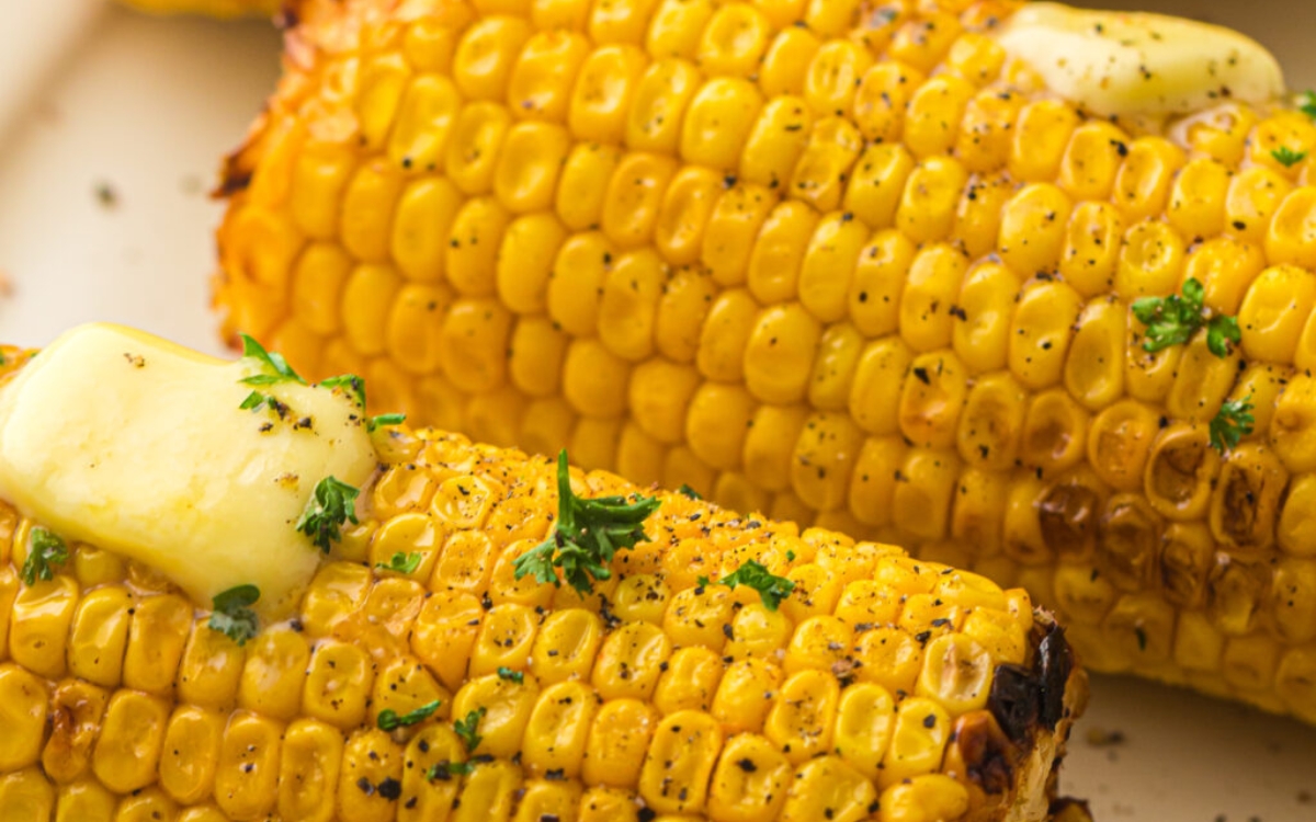 Grilled corn on the cob topped with melted butter, chopped parsley, and black pepper.
