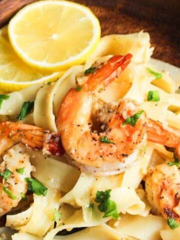 pasta, shrimp and slice of lemon on a wooden bowl