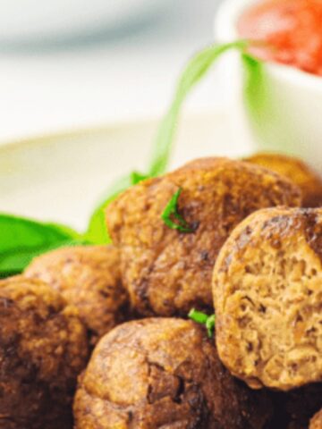 meatballs on a plate with red sauce on a bowl on the background