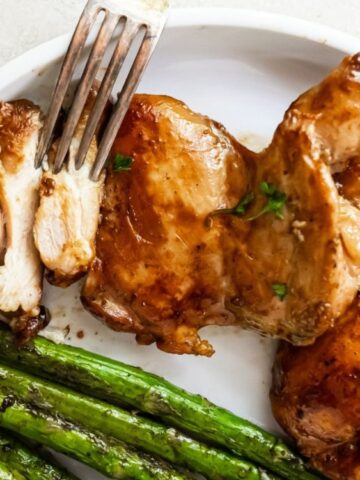 chicken teriyaki on a plate with asparagus and fork on the side