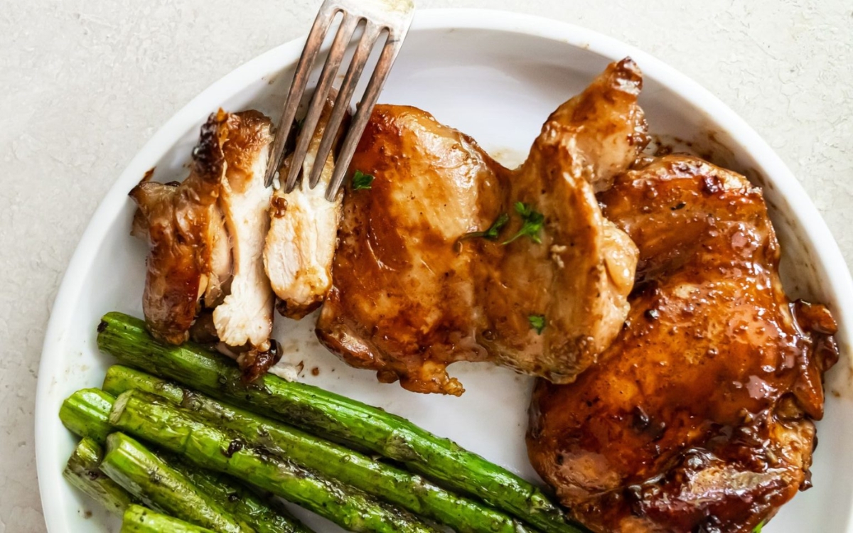 chicken teriyaki on a plate with asparagus and fork on the side