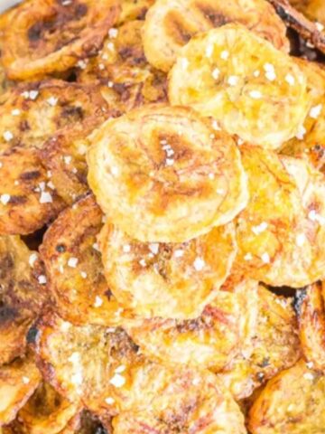 A bowl of baked plantain chips sprinkled with coarse salt.