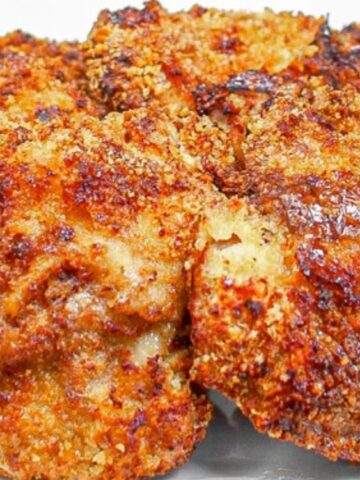 Five golden-brown, crispy breaded chicken thighs arranged on a white square plate.