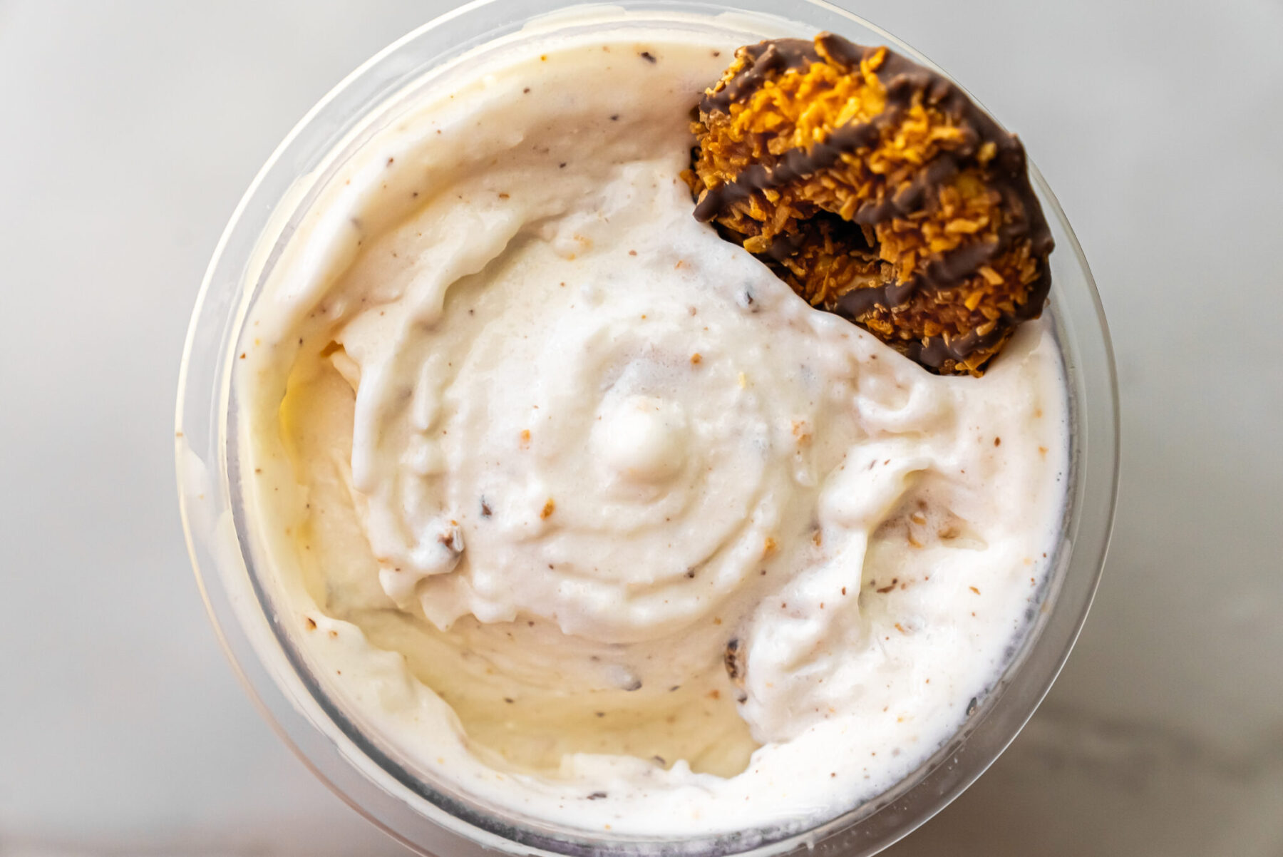 Detailed overhead shot of smooth, vanilla-caramel ice cream in Ninja Creami pint, speckled with cookie crumbs and crowned with a chocolate-drizzled Caramel DeLite.