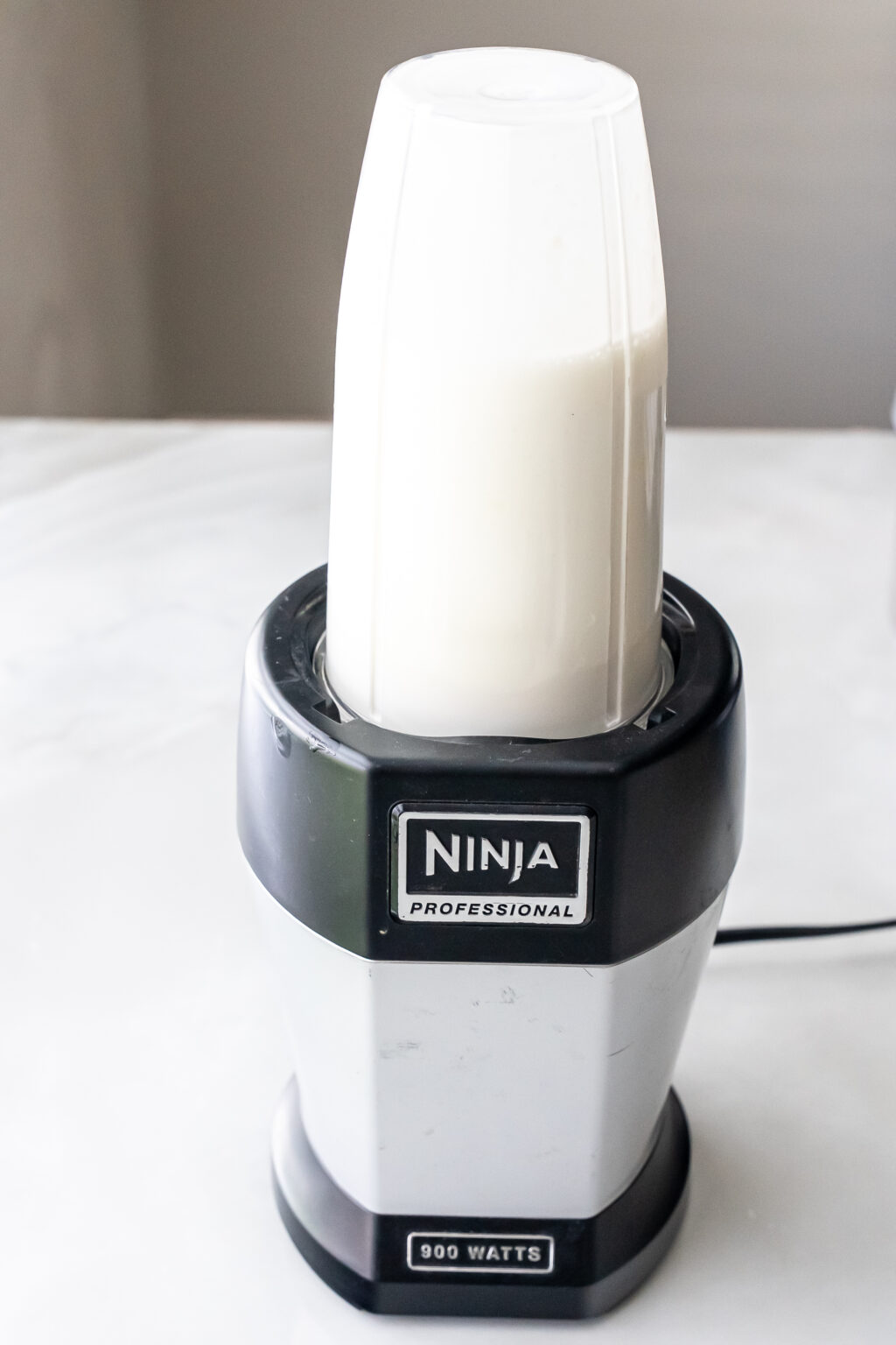Ninja Professional blender with tall cup filled with white liquid base.