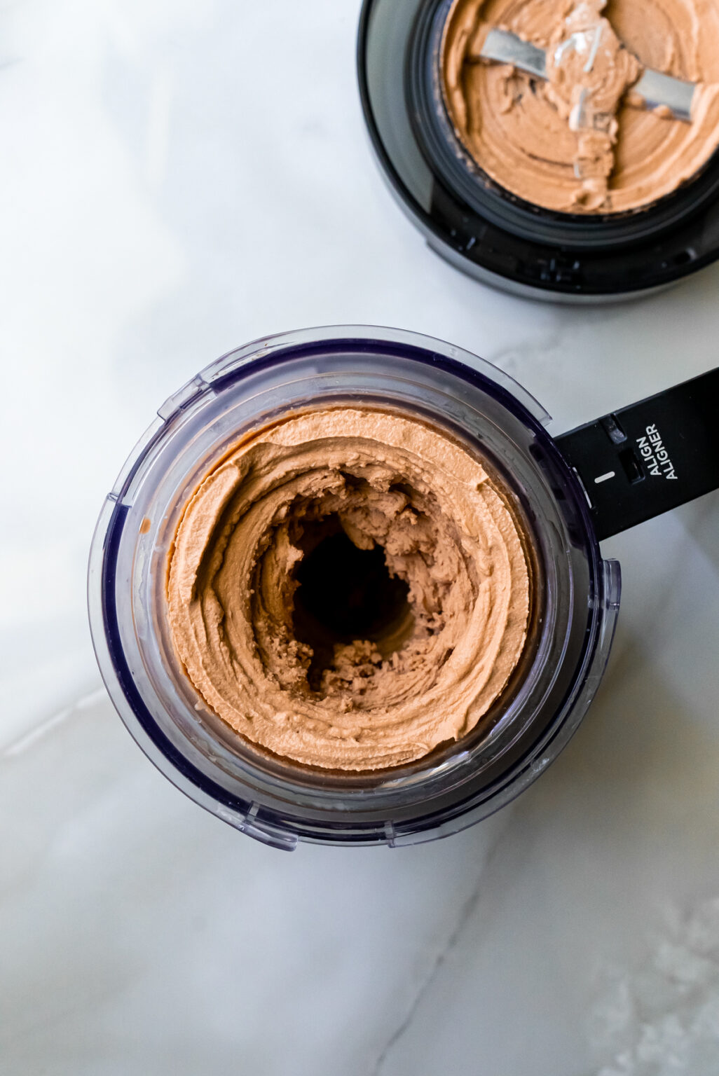 Top view of a pint containing a swirled chocolate ice cream with the lid nearby.