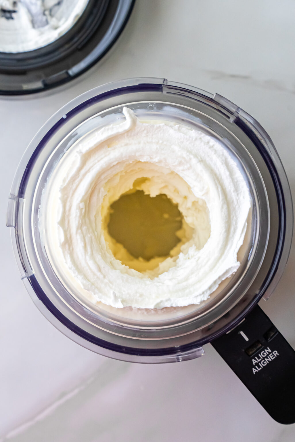 Overhead shot of improved, creamy white ice cream in a Ninja Creami pint with a hollow center well after re-spin, preparing for mix-ins in High Protein Caramel Chocolate Chip Ninja Creami Ice Cream recipe.