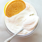 Overhead view of Lemonades Ninja Creami Ice Cream in a pint. An ornate silver spoon rests in the white ice cream, and a whole Lemonades cookie sits on the upper left edge of the container.Overhead view of Lemonades Ninja Creami Ice Cream in a pint. An ornate silver spoon rests in the white ice cream, and a whole Lemonades cookie sits on the upper left edge of the container.