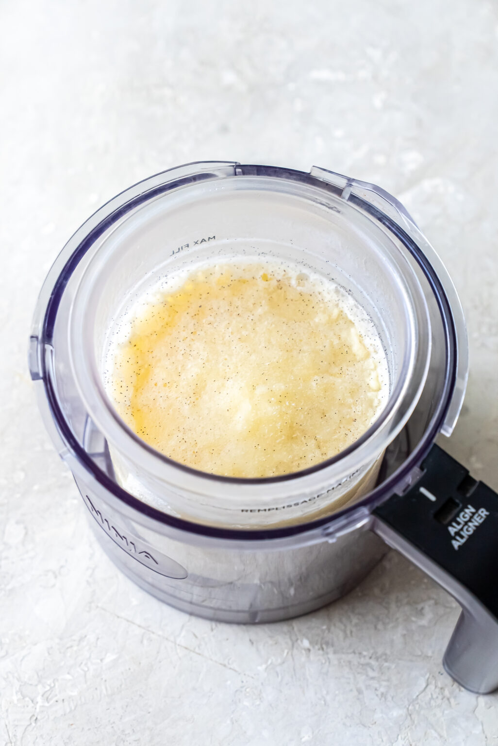 Overhead shot of the frozen Mint Chocolate Protein Ice Cream base inside a clear Ninja Creami pint, placed within the machine's outer processing bowl, ready for spinning.