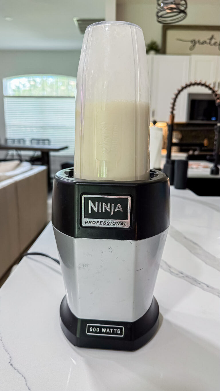A Ninja Professional blender cup attached to its base, blending a creamy white liquid mixture to create the smooth base for Ninja Creami Banana Ice Cream with protein powder.