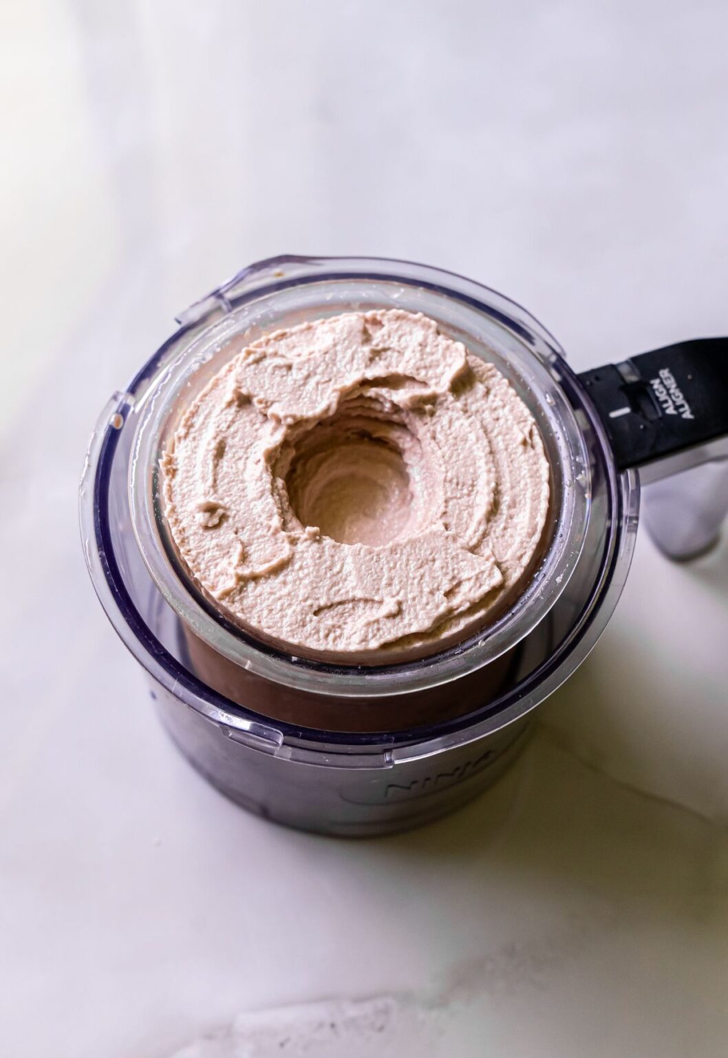 Top view of high protein chocolate ice cream swirled in a clear Ninja blender pint.