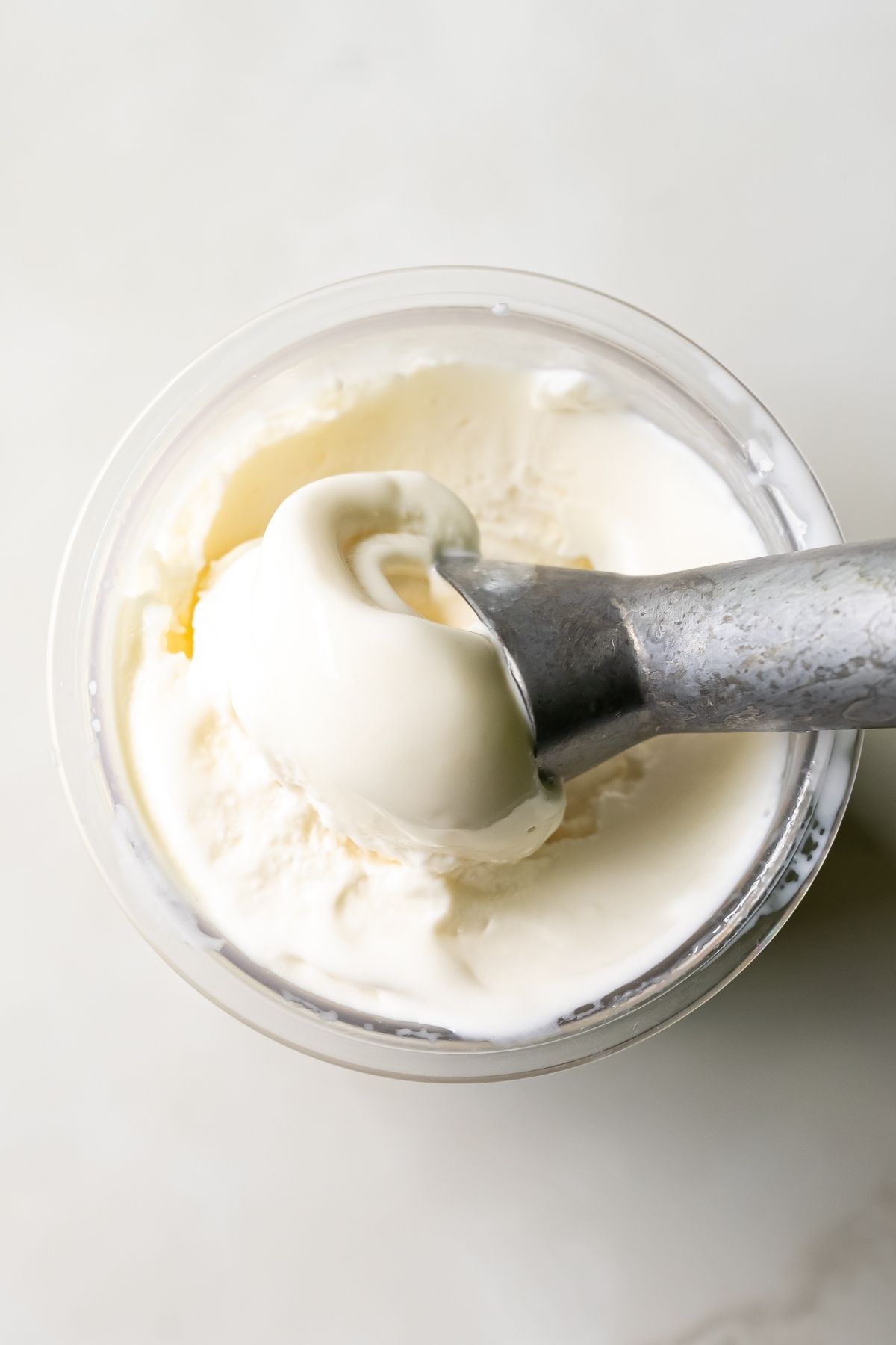 A metal spoon scoops a portion of protein ice cream from a clear container, perfectly prepared by the Ninja Creami.