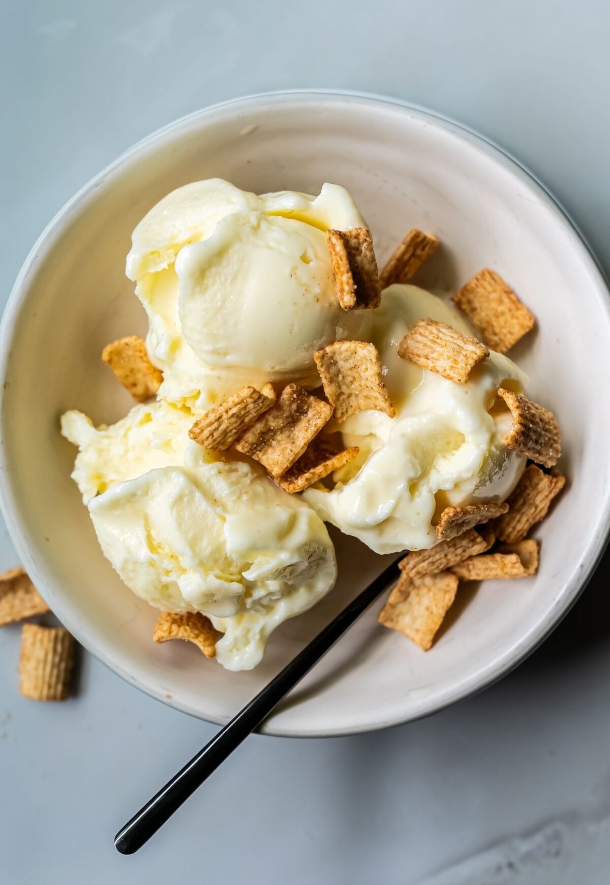 A bowl of banana ice cream, transformed by the Ninja Creami, is topped with cereal pieces and a spoon for a low-carb delight.