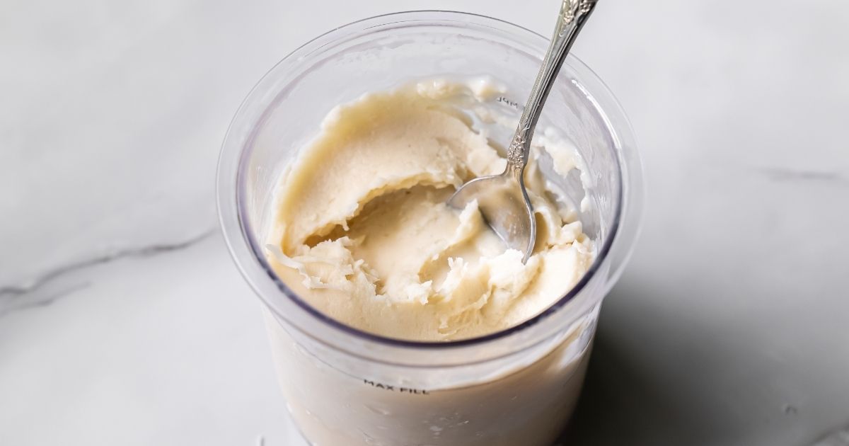 Ninja Creami Oat Milk Coconut Protein Ice Cream in a clear pint with a metal spoon inside.