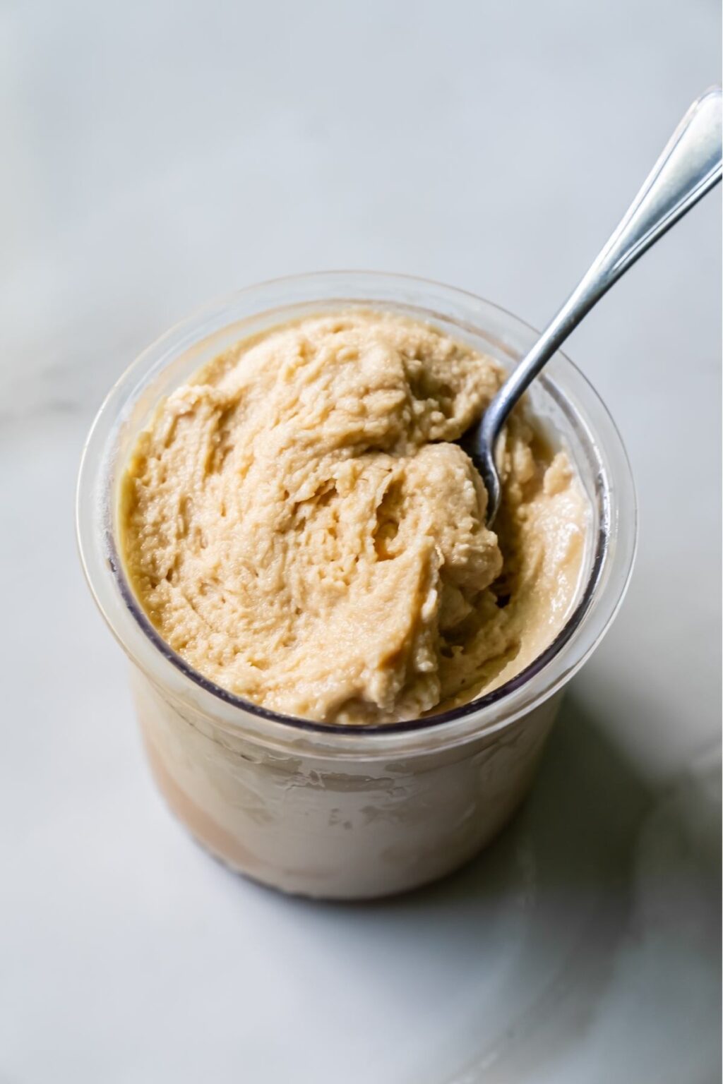 Oat Milk Protein Coffee ice cream in a clear pint with a spoon