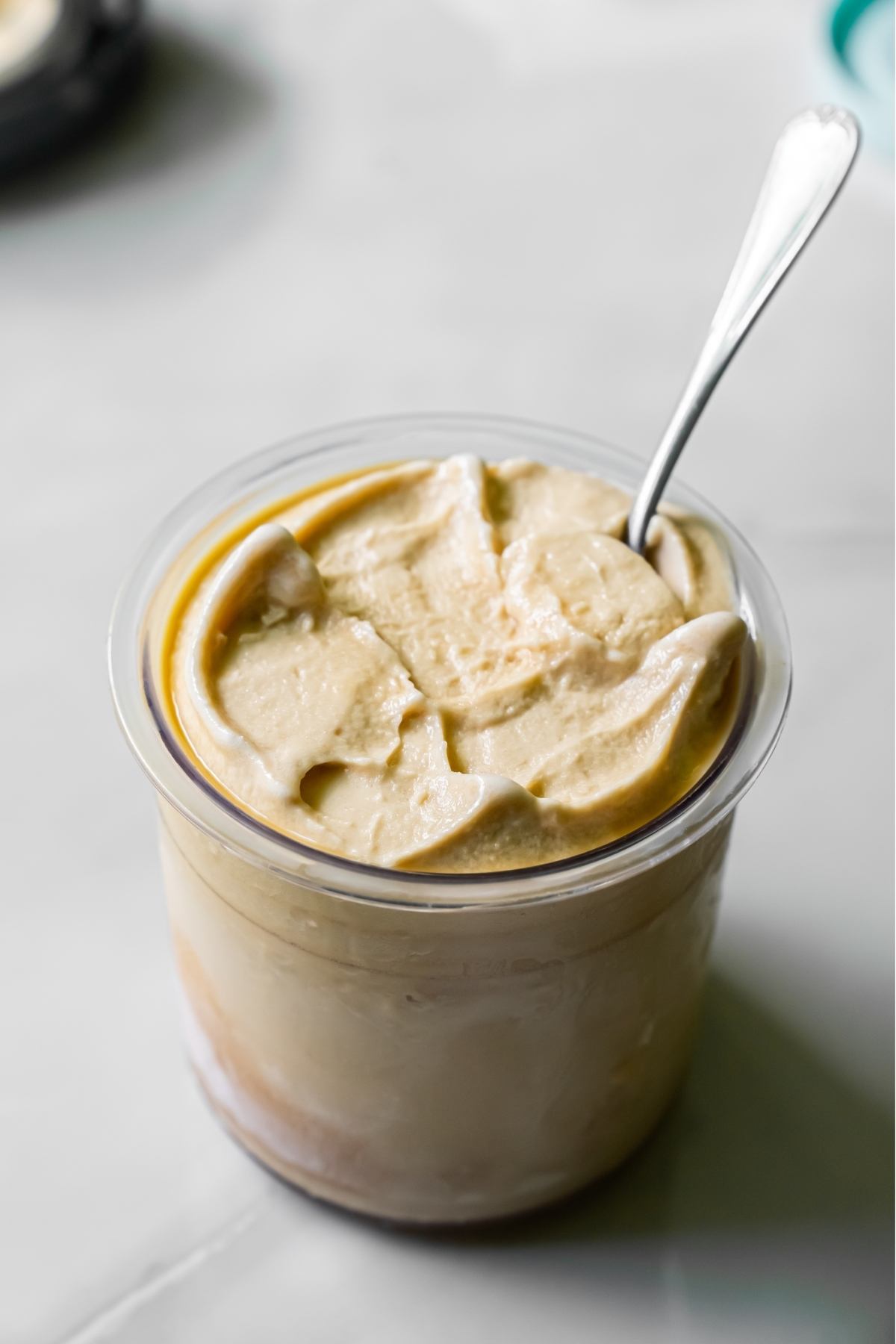 Oat Milk Protein Coffee ice cream in a clear pint with a spoon