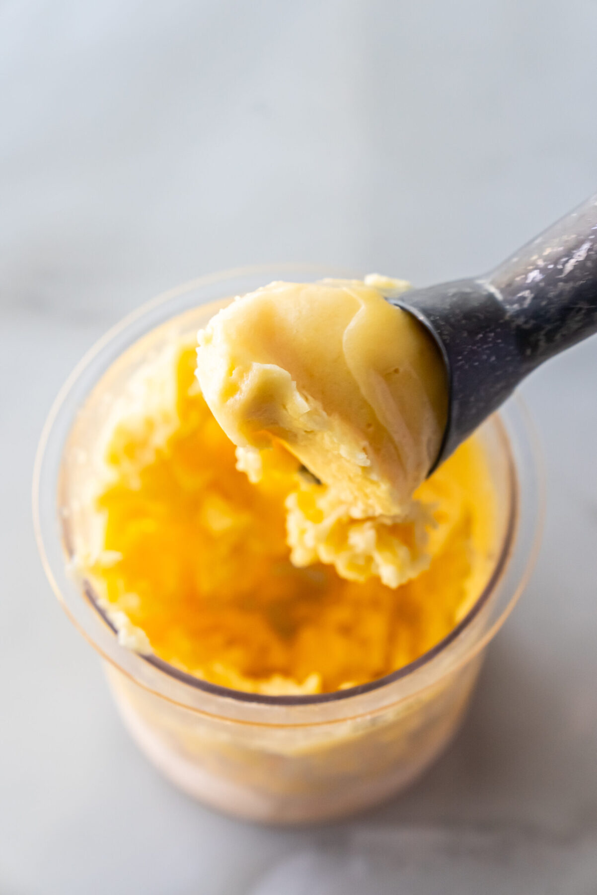 peach sorbet in a pint with an ice cream scooper.