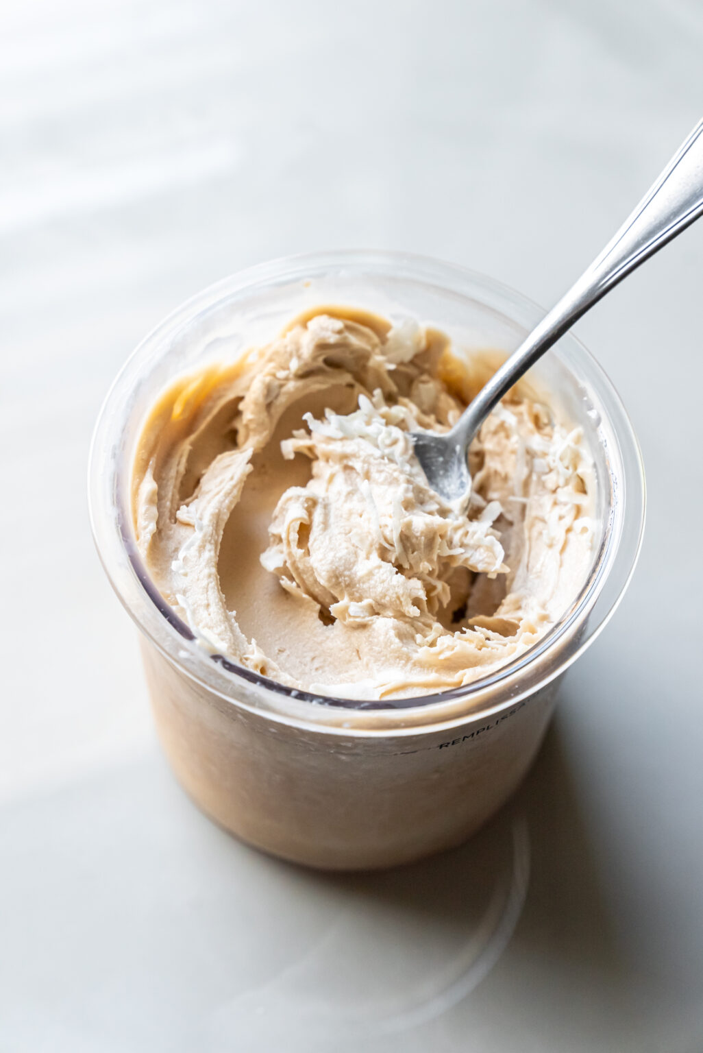 A spoon is placed in a bowl of Ninja Creami Pina Colada Protein Ice Cream.