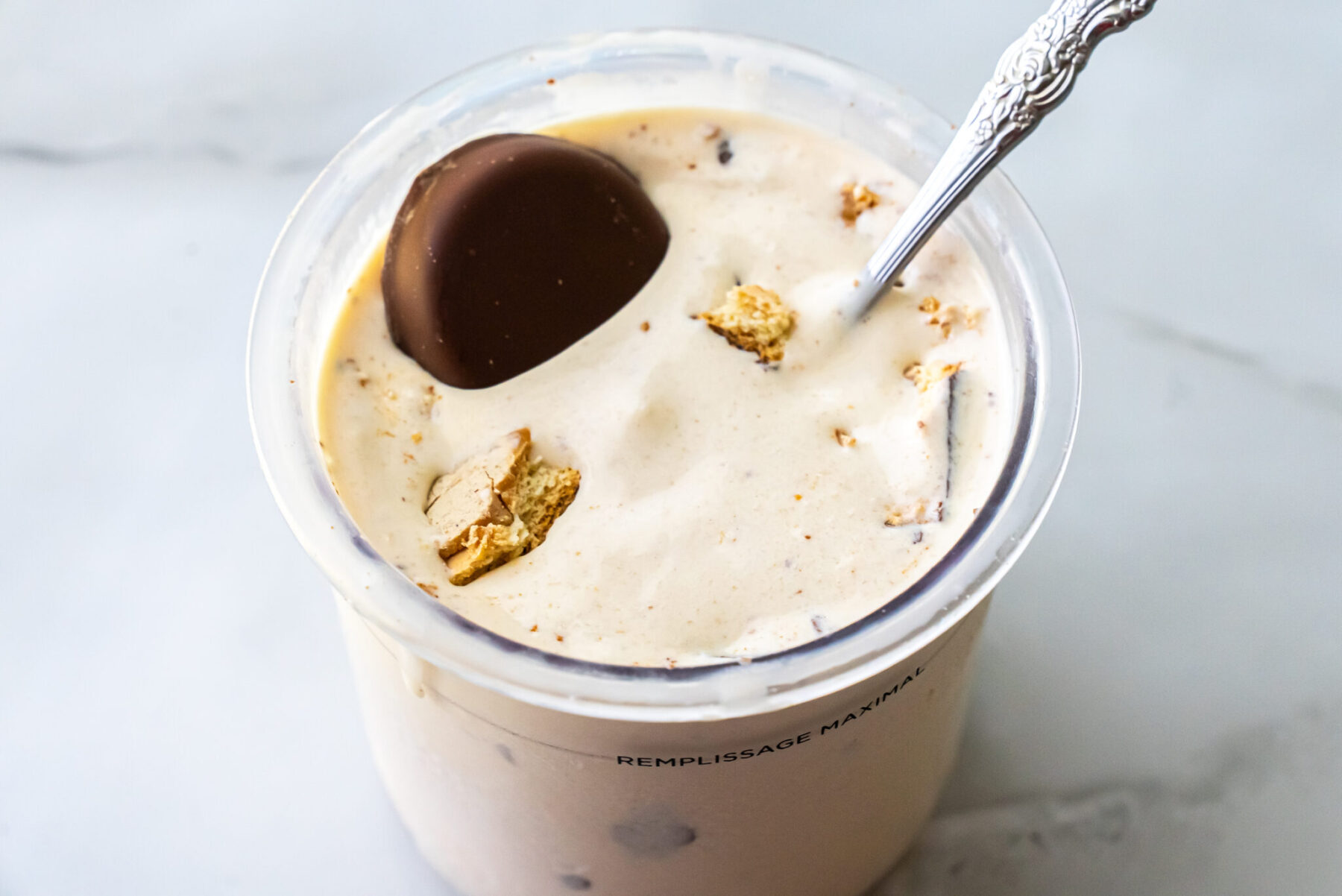 Close-up of Peanut Butter Patties Ninja Creami Ice Cream in a pint with a silver spoon. A whole cookie rests on the surface. A red bag of Girl Scout Peanut Butter Patties is visible in the blurred background.