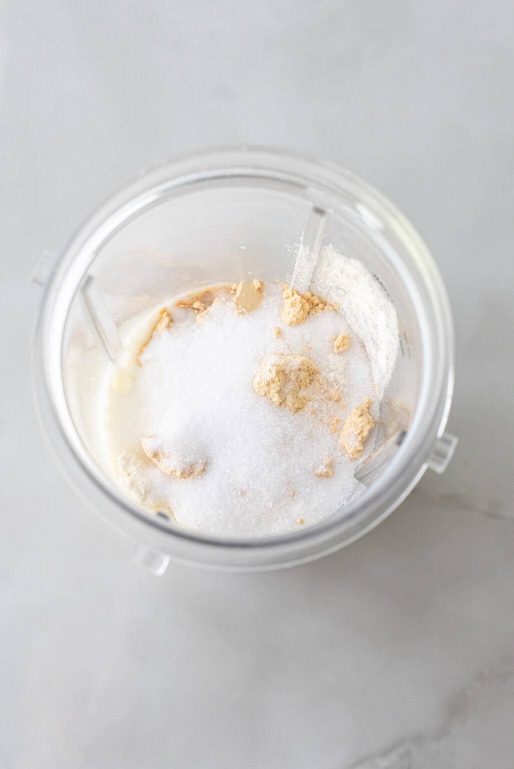 Top-down shot of white protein powder and PB2 peanut butter powder inside a clear Ninja blender cup, preparing the dry mix for Peanut Butter Patties Ninja Creami Ice Cream base.
