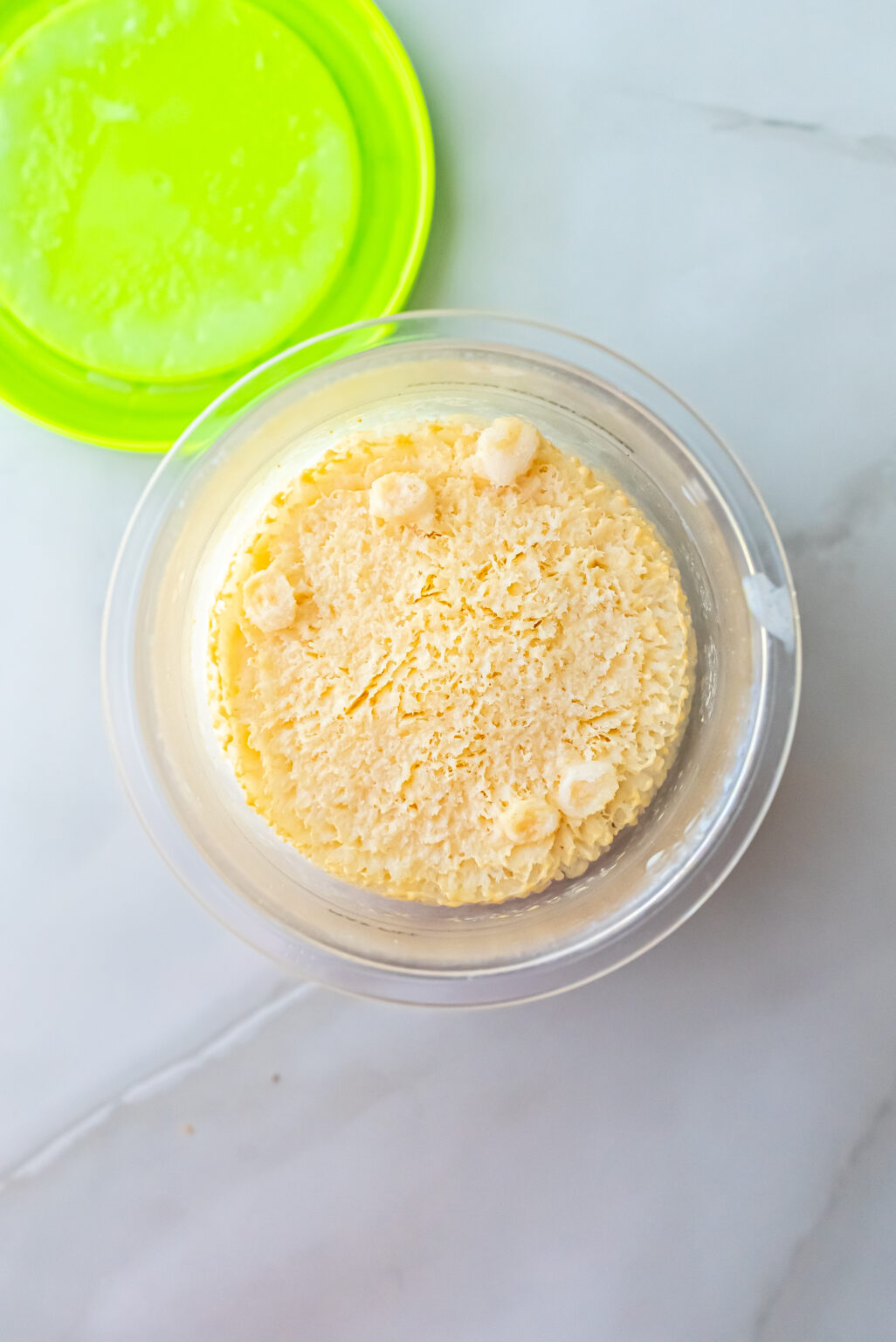 Overhead view of a clear Ninja Creami pint filled with smooth beige liquid base for Peanut Butter Patties Ninja Creami Ice Cream, frozen before processing.