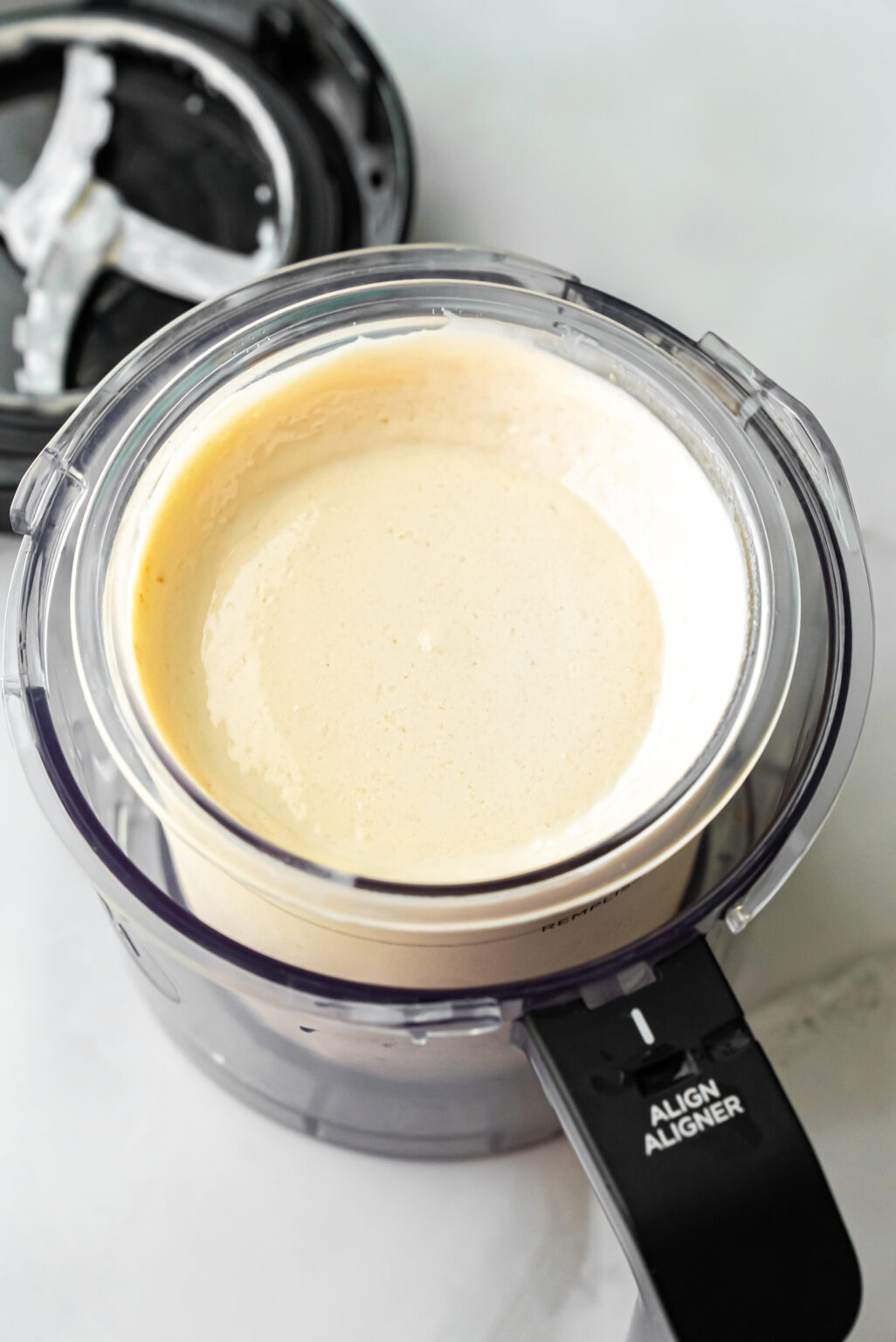 Top-down view of churned white ice cream in a Ninja Creami pint with a hollow center well, showing the texture after the initial spin cycle for Peanut Butter Patties Ninja Creami Ice Cream.