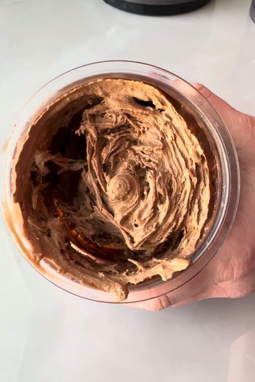 Close-up overhead shot of perfectly swirled, velvety Thin Mint Protein Ice Cream in pint after re-spin and mix-in